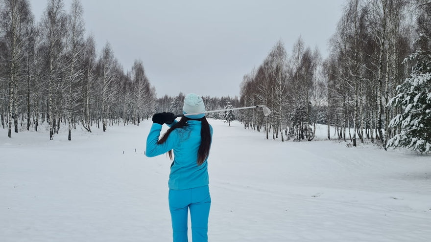 woman dressed in blue winter attire playing golf